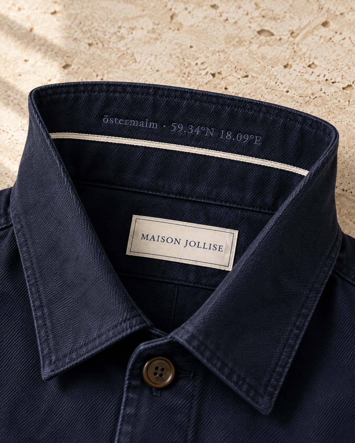 the canvas overshirt in navy · östermalm — collar turned up, coordinates embroidered underneath
